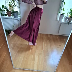 Vinröd långkjol  - Ursnygg röd långkjol. Har haft tanke på att klippa slits, men andrig blivit av. Hoppas nästa person får dansa loss i denna med! // 36/38