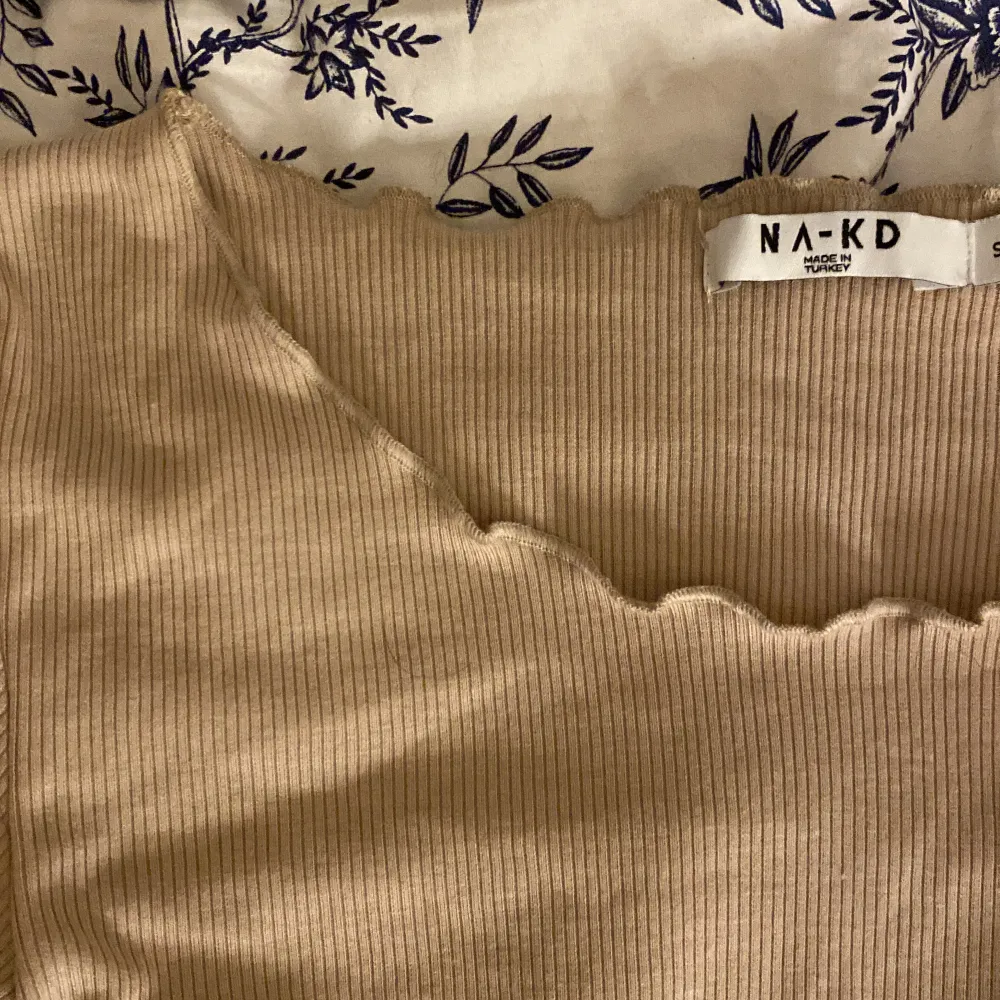 En tunn ribb stickad tröja från NA-KD, helt oanvänd. Super mjuk i material och har volang detaljer vid slutet av armarna och längst ner på tröjan. Jättefin beige färg . Stickat.