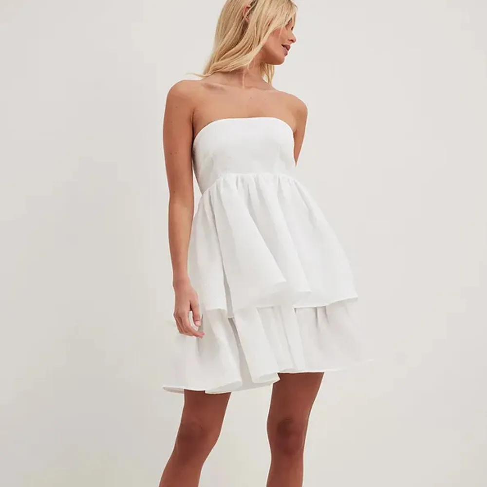 Säljer nu dennna super fina vita volang bandeau klänningen från NA-KD som nästan alltid är slutsåld. Strl 38 men skulle säga att den är lite större en en ”vanlig” 38. Perfekt till studenten, konfan eller sommar. Helt ny, med lapp och allt kvar🤍. Klänningar.