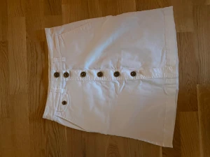 Vit jeans kjol - Vit jeans kjol, använd 1-2 ggr. Ser helt ny ut. Knappt framtill, fickor bak.
