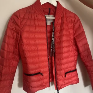Moncler jacka  - En röd moncler jacka i storlek xs. QR-kod finns. Säljer pga att den inte kommer tlll användning. Inga defekter.  Skriv för fler bilder. Ljuset gör inte färgen riktigt rätt. Köparen står för frakten, inga retuer.🥰