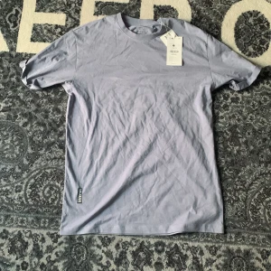 Helt Ny T-Shirt - Helt ny t-shirt. Ljusblå ish färg. 