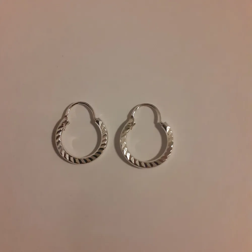 Örhängen i äkta silver. Supervackra små ringar med mönster. Helt oanvända.  Ask: 10 kr (valfritt) Frakt: 15 kr. Accessoarer.