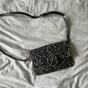 Mönstrad väska - Vet ej vart den är köpt. Mönstret är snakeprint och det är ett långt band på den.