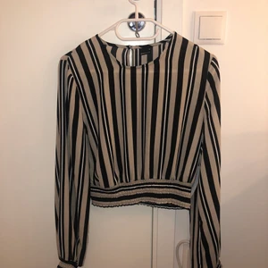 randig gina tricot blus  - en randig gina tricot blus jag aldrig använt, fick den i present och lappen är fortfarande kvar. den är beige, vit och svart. väldigt fin och väldigt blus material. köpt för 250 kr och som ny 