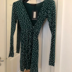 Prickig wrapdress  - Mörkgrön wrapdress med prickar från prettylittlething. Inköpt för 3 år sedan men aldrig använts, prislapp kvar. Storlek 36