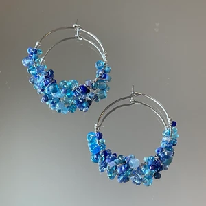 Örhängen  - Handgjorda örhängen med med glas- och stenpärlor i olika storlekar fastvirade med silvrig ståltråd. Ca 4 cm i diameter. Säljs separat för 100kr, 2 par för 175kr  ⭐️Frakt tillkommer på 39kr!!!  Checka min profil för mer 💜