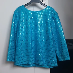 Blå glittring blus - Skräddarsydd topp som passar bra till fest eller finare middagar. Knappar i ryggen, 3/4 armar. Endast använd två gånger. Passar till den blå kjolen jag säljer. Sorlek ca 134-140. Köparen står för frakt. Dm vid intresse.