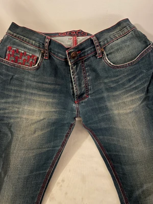 Jättesnygga lågmidjade Taracci jeans -  Jätte coola baggy och lågmidjade Taracci jeans med röd söm 😻 Säljer då den inte kommer till användning längre :( Den är i väldigt bra skick förutom att den är lite sliten vid fickorna som man kan se på bilden.
