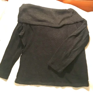 Svart stickad tröja med off shoulder krage - Säljes pga dubbelköp. Oanvänd. Längd 50cm. Har använt ”tvillingen” och den är mkt mjuk och skön. Elastisk 