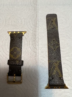 Louis Vuitton Armband - L&V armband till apple watch 44mm passar Apple watch series 6. Bandet är från en äkta Louis Vuitton väska speciellt gjort för apple watch, bra skick och hållbart.