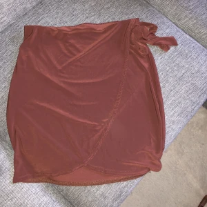 NLY ONE kjol med knytdetalj - Jättefin, brun kjol i tunnare tyg men ej genomskinligt. Knytdetaljen har emdast dekorativt syfte som visas på bild.  Endast provat 1 gång.  Katt finns i hemmet!