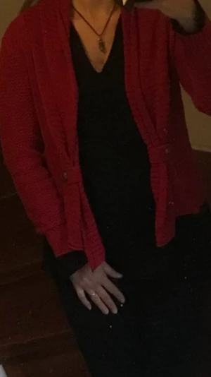 Snygg julröd kofta  - Vacker öppen kofta i 100% bomull. Halskrage som viks bakåt och går ner på framsidan och knäpps åt sidan med en knapp på varje sida.  Snygg speciell på julfesten. Storlek S men är rymlig. Personen på bilden är 168cm och väger 65kg. 