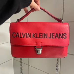 Calvin Klein handväska Sculpted Flap13.5 - Säljer min fantastiskt fina handväska i skinnimitation från Calvin Klein. Väskan är i gott skick! Den heter Sculpted Flap 13.5 och kostar ca 1500kr i nypris. Jag säljer den för 800kr. Finns i Kungsbacka, men kan också skicka 🥰 Då betalar köparen frakten. 