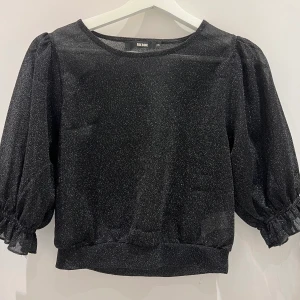 Festtopp - Glittrig festropp med puffiga ärmar. Kortare modell