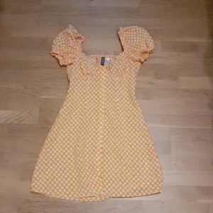 En fin orange klänning med vita blommor - En fin orange klänning som inte kommit till andvänding (aldrig andvänt) 