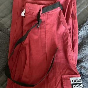 Adidas byxor  - Oanvända Röda adidas byxor med svart bälte som medföljer.  