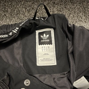 Adidas - Ett par adidas skid överdragsbyxor i strl S. De är lite bredare längst nere som bootcut typ. Byxorna har några lagade hål och slitage på nedre delen av benen och de är ganska slitna på rumpan