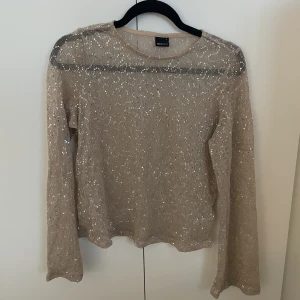 Genomskinlig paljetttopp/blus - En beige/guldig, till viss del genomskinlig, paljettblus/topp från gina tricot. Använd några få gånger, kanske två eller tre. 