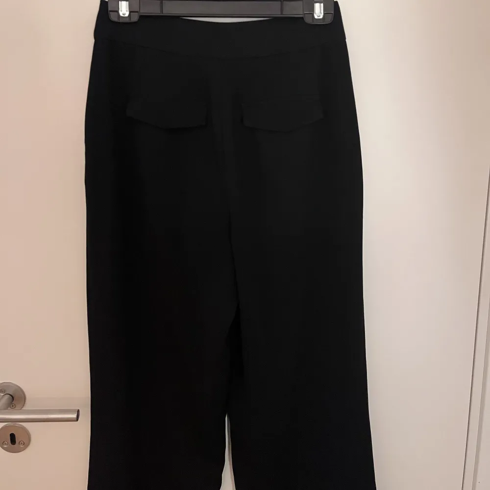 Svarta kostymbyxor med bredpassform i benen, köpta på newyorker. Snygg detalj vid bakfickan.. Jeans & Byxor.