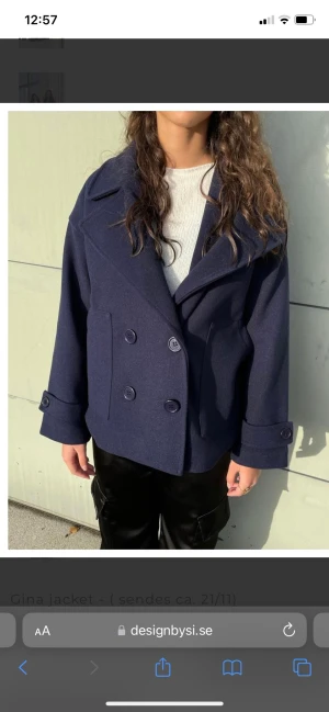 Marinblå kappa - Säljer en jättefin marinblå, lite kortare, kappa från ”Design by Si”. Ej använd och lappen sitter kvar. Passar perfekt på hösten eller som lite finare vinterjacka! Köparen står för frakten