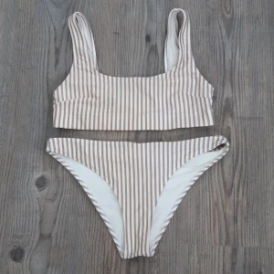 Bikini - Vit och beigerandig bikinitopp och trosor från HM i strl 38. Toppen är använd en gång och trosorna aldrig. Det är såklart tvättat.