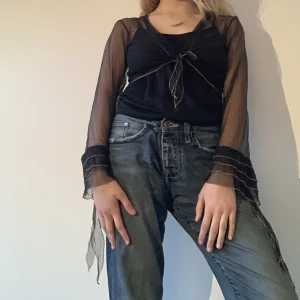 Svart knytblus  - Svart knytblus i genomskinligt material, med fin guld detalj. Påminner mig om Stevie Nicks. 