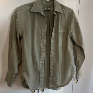 Grön skjorta - Grön skjorta i ett tjockare material. Mellanting mellan jacka och skjorta. Färgen stämmer mest överens med bild två. Nästan aldrig använd 
