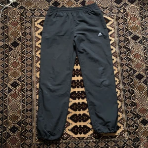 Adidas byxor - Adidas byxor med drag kedja längsner. Man kan dra åt vid fötterna för different shape. Längd ca 105 cm. Innerben ca 80cm. Midja 39cm utan stretch. Kan bli bredare och smalare, finns snöre. Storlek M