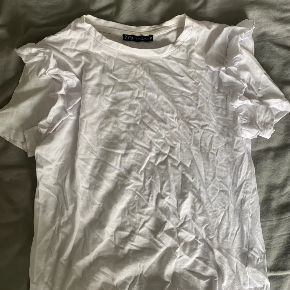 En vit T-shirt med volanger vid axlarna⭐️Så fin till jeans, kjol etc. T-shirts.