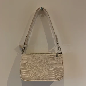 Handväska Urban Outfitters - Cremefärgad liten handväska från Urban Outfitters. Fint skick utan skador eller märken. 