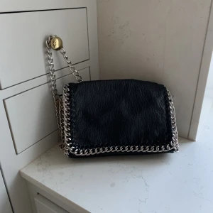 Svart väska  - En svart väska med kedjerem. Rymmer mycket.