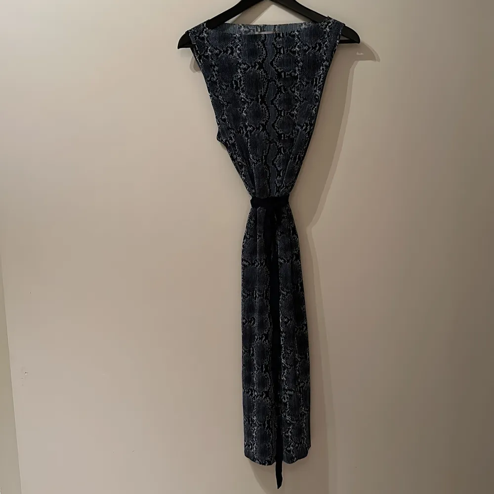 Ursnygg klänning i svart/blå snake skinn mönstring, lite creppat tyg. Hällor hela och band/skärp. Medium men både small o large kan ha den.. Mekot.