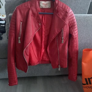 Skinnjacka  - Röd skin jacka. Inköpt för längesen me aldrig använt, bara blivit hägandes i garderoben. Från chiquelle har ja för mig. 