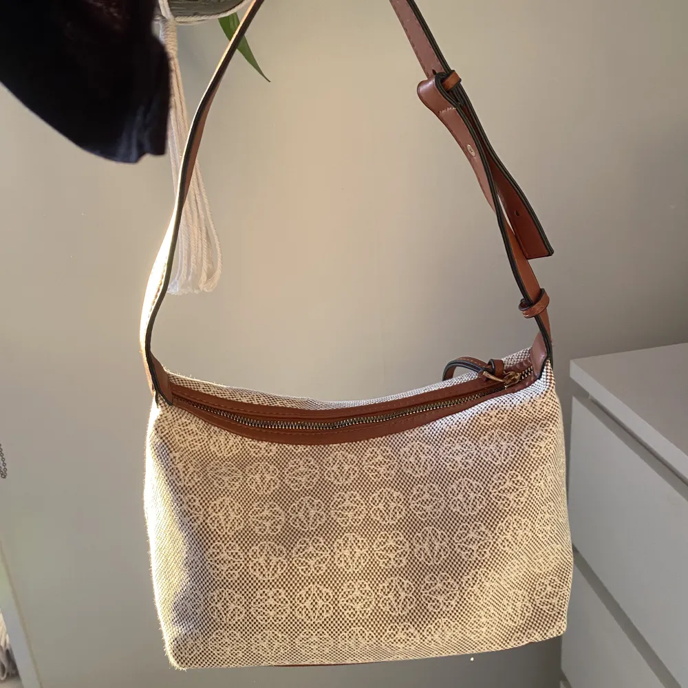 Snygg rymlig baguetteväska med fint beige/vitt mönster och bruna detaljer. Justerbart band för att kunna bestämma längden på väskan 🤍. Väskor.
