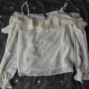 Delikat långärmad blus med krusiduller - Delikat långärmad blus med krusiduller.  Ny och oanvänd.  Blusen är lätt och luftig och ganska styv, och materialet är tunt, så du måste välja en bra bh.