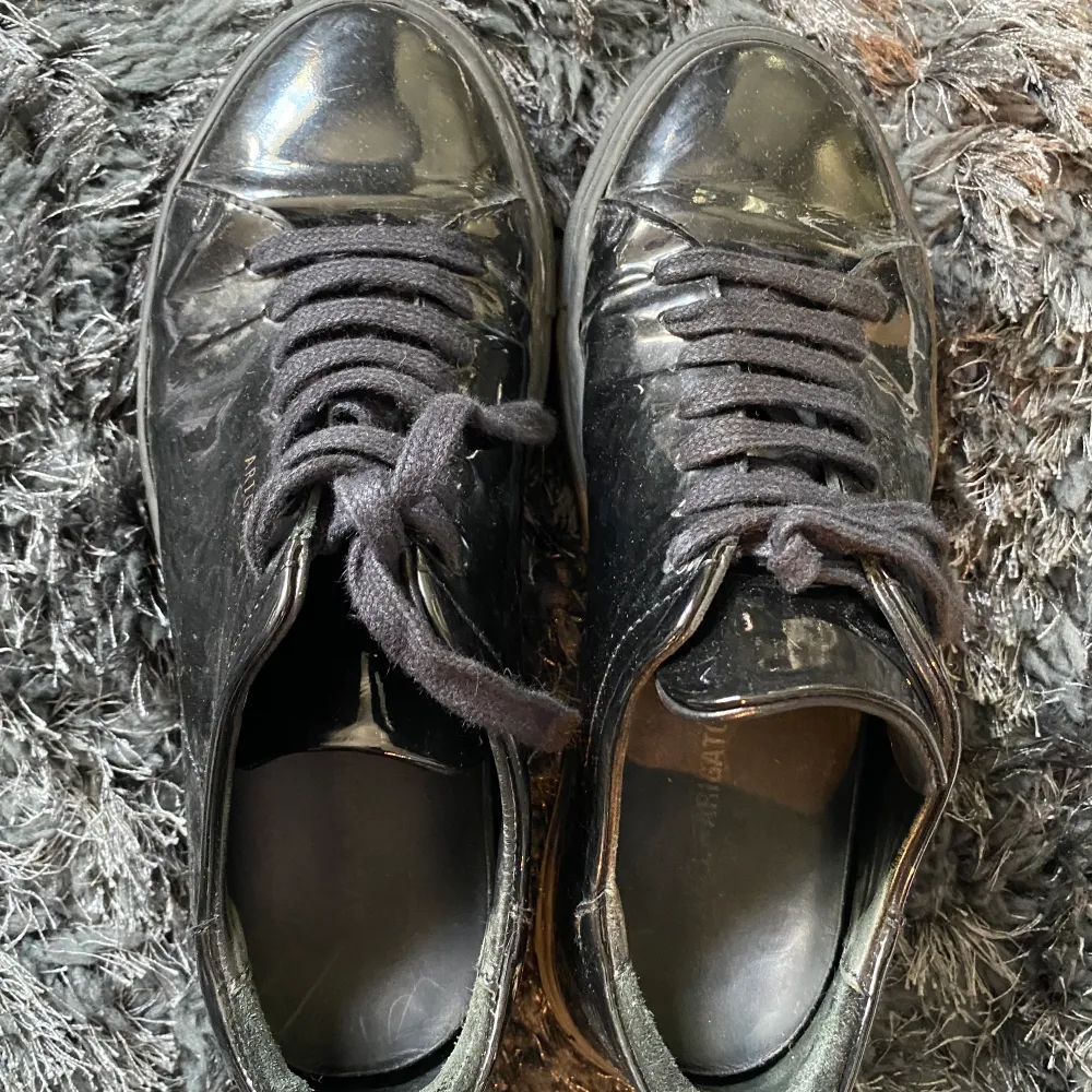 Glansiga svarta skor från Axel arigato. Bra skick, lite repiga men inget som man tänker på vid användning. Pris kan diskuteras vid snabb affär. Köpare står för frakt 99kr. Skor.