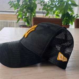 New Era, NY trucker keps - Svart camouflagemönstrad trucker keps med guldig brodyr i fint skick. 