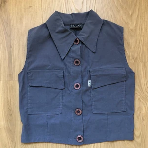 Ärmlös skjorta croppad - Ärmlös skjorta i den snyggaste grå-blå färgen. Något stretch i vilket gör att den passar ens kropp väl! Något croppad. Viskos. Passar 34-38  helt beroende på om den ska sitta löst eller mer tight