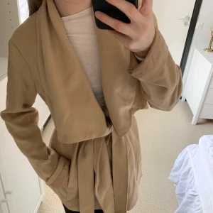 Beige trenchcoat  - Beige trenchcoat från Dennis Maglic! Den är i storlek L men som ni ser på bilden är den en liten modell.
