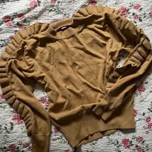 En finstickad mörkbeige tröja med populär volangdetalj från H&M. Helt i nyskick, utan defekter, i storlek 34. Frakt tillkommer💕
