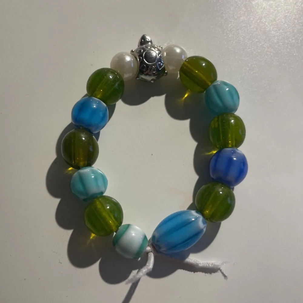 Armband med glaspärlor i grön, vit och blå och en silvrig sköldpadda. ❤️🐢. Accessoarer.
