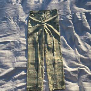 Ett par gröna rutiga byxor, med bruna, vita och gula detaljer. Extremt fina men aldrig använda.  