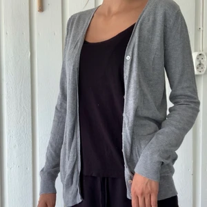 Grå stickad kofta - Små fickor fram, knappar, swipe för bild. Amisu, strl M