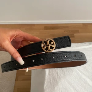 Tory Burch Bälte - Tory Burch Bälte i svart, Nypris 2365 kr, gjort 5 extra hål i bältet så passar XS, S, M, Bra skick, bara lite slitningar på metallen men syns knappt, speciellt inte från normalt avstånd/långt avstånd bara om man kollar väldigt nära, men därav priset