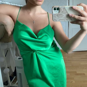 Grön sommarklänning  - Säljer denna fina klänningen. Den är i ett slags silkesmatreal och passar perfekt i sommar. Urringningen där bak var väldigt låg för min smak, annars är den superfin och inte använd. Helt ny.