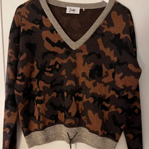 Isay tröja - V-ringad stickad tröja med lurextrådar (glittriga guldtrådar). Dragsko i linning. 