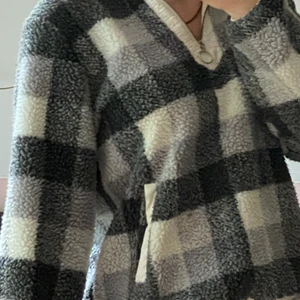 Fluffig tjocktröja - Rutig grå och vit tjocktröja med kort dragkedja. Bra skick förutom att den är lite fläckig runt kragen.  Säljer pga att den inte är min stil längre. Kan mötas upp eller posta.     Storlek M men den är väldigt pösig!