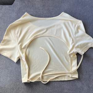 Superfin t-shirt med öppen rygg. Som ny! Storlek M/S! Stretchigt material, ljusgul/beige som på bild