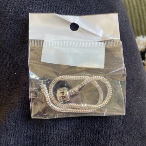 Pandoraarmband - Armband med texten Pandora, ser exakt ut som ett äkta men är alltså en kopia. Man kan sätta berlocker på som vanligt! OANVÄNT i förpackning!! 